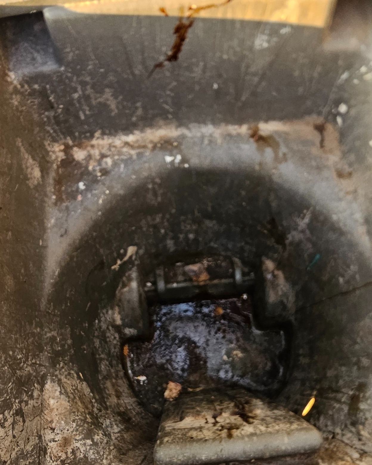 Inside of a dirty trash bin with heavy residue before cleaning